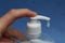 Finger presses white dispenser in a plastic bottle