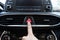 Finger pressing a hazard warning lights button on a modern luxury korean car