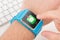 Finger taps messenger icon on blue smart watch