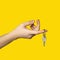 On finger of woman hand hangs key on bright yellow background. Give key to house or office.