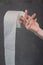 On the finger of a woman`s hand holding a roll of toilet paper on a gray background