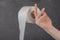 On the finger of a woman`s hand holding a roll of toilet paper on a gray background