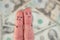 Fingers art of displeased couple on background of money.