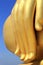 Fingers of biggest golden buddha statue on blue sky background