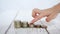 The fingers of the child touch a stack of coins of money on a white background, imitating the movement of the feet over