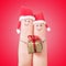 Fingers faces in Santa hats with gift box. Happy couple concept