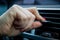 Fingers of a female hand hold and move the adjustment lever of the air duct flap in the interior of a modern car. close