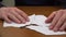 Fingers fold a sheet of paper from torn scraps
