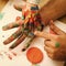 Fingers and hands drawing with multicolor paints on white paper