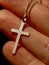 Fingers holding silver cross necklace