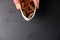 Fingers are holding a small white plate full of brown pecans on a black background