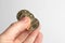 Fingers holding three Ukrainian coins on a light background