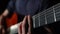 Fingers of man on neck of acoustic guitar plucking strings, playing rock in studio, closeup. Man plays an acoustic