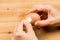 Fingers peeling hard boiled egg on wooden table