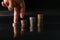 Fingers step upward on stack of coins on black background concept business finance growing