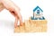 fingers stepping up on wooden blocks to miniature house on wooden board on a white background.The concept of growth in business.