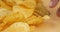 fingers take golden potato chips closeup, fried salty snack