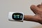 Fingertip pulse oximeter equipment connected to the index finger of a young man measuring oxygen saturation and heart rate