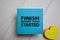 Finish What You Started write on a sticky note  on Office Desk