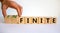 Finite or infinite symbol. Businessman turns wooden cubes and changes the word `finite` to `infinite`. Beautiful white table,