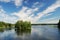 Finnish lake with green islands under summer sky.