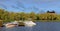 Finnish landscape. Boats and yachts on pier on Vanajavesi lake against backdrop of park and fortress. Hameenlinna, Suomi