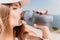 Fintess woman drinking water. Happy, active middle aged woman standing on beach and drinking water after excersise