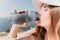 Fintess woman drinking water. Happy, active middle aged woman standing on beach and drinking water after excersise