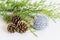 Fir branch, three pinecones and tinsel holiday decoration on white background