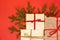 Fir branch / twig and christmas gift boxes on red background. Bu