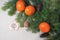 Fir branches, tangerines and handmade Christmas toys and mouse on a light flax background. View from above. Copy space