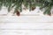 Fir leaves and pine cones decorating rustic elements on white wood table with snowflake