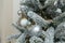 Fir tree branches covered with artificial snow, white and silver bulbs, baubles, golden garlands. Christmas tree closeup