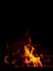 Fire on a black background. Red, orange and yellow flames and sparks on a dark background. Bonfire, fireplace, hearth or fire