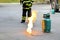 Fire burning on green gas container and Firefighter or fireman in black and green safety uniform or suit and extinguish fire.