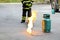 Fire burning on green gas container with Firefighter or fireman in black uniform and wheel background