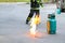 Fire burning on green gas container with Firefighter or fireman in black uniform and wheel background during fire safety training