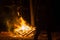 Fire on a dark background. Bonfire in the forest. Flames throw sparks. Camping and outdoor recreation. The wood is on fire. The