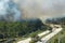 Fire department firetrucks extinguishing wildfire burning severely in Florida jungle woods. Emergency service vehicles