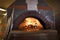 Fire in dome ceramic wood burning pizza oven at Amsterdam Brewhouse Toronto