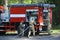 Fire engine parked, firemen team preparing fire-fighting equipment for use