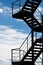 A fire escape or an external staircase on a building silhouetted against a bright sky