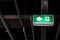 Fire exit sign hanging under ceiling. Selective focus and shallow depth of field.