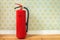 Fire extinguisher in front of retro flower wallpaper
