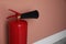Fire extinguisher near color wall indoors. Space for text