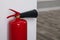Fire extinguisher near white wall, closeup. Space for text