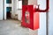 Fire hose in red box. Pipe roll for fire emergency in red metal cabinet on grey whitewashed wall as part of fire