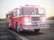 Fire truck running with lights and sirens on a street with motion blur.