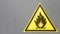 Fire warning icon, sign on a yellow label on a gray background. Flammable. Yellow triangle on a metal wall. Background with copy