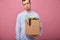 Fired sad guy in blue shirt and glasses holds cardboard box with different things